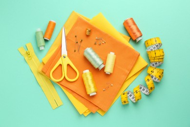 Flat lay composition with different sewing supplies on turquoise background