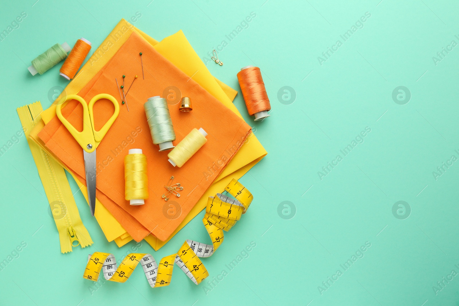 Photo of Flat lay composition with different sewing supplies on turquoise background. Space for text