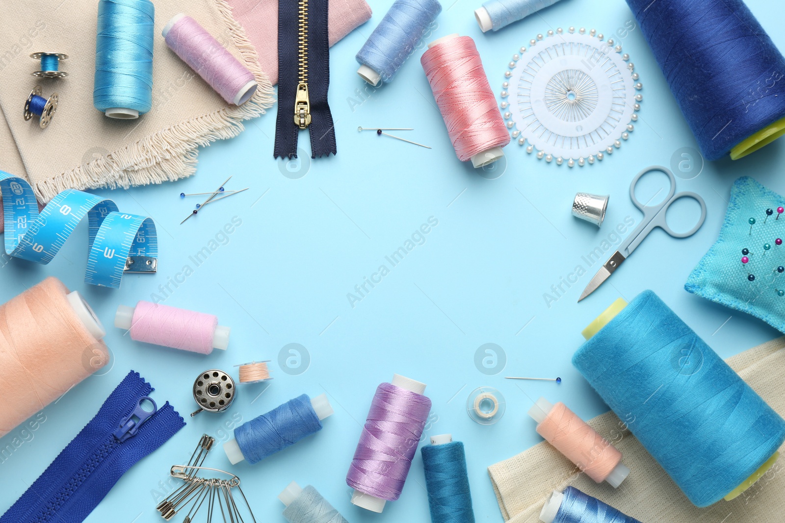 Photo of Frame of different sewing supplies on light blue background, flat lay. Space for text