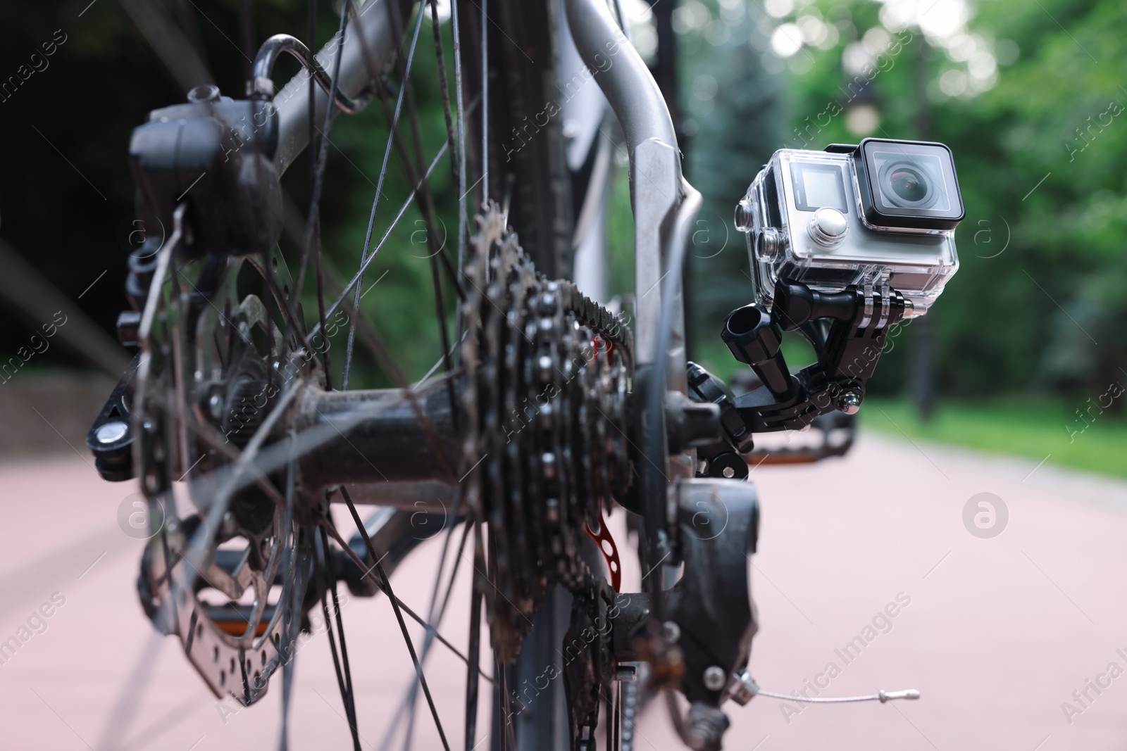 Photo of Modern action camera with mount on bicycle outdoors, closeup