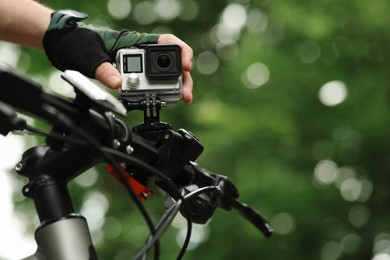 Man with modern action camera on bicycle outdoors, closeup. Space for text