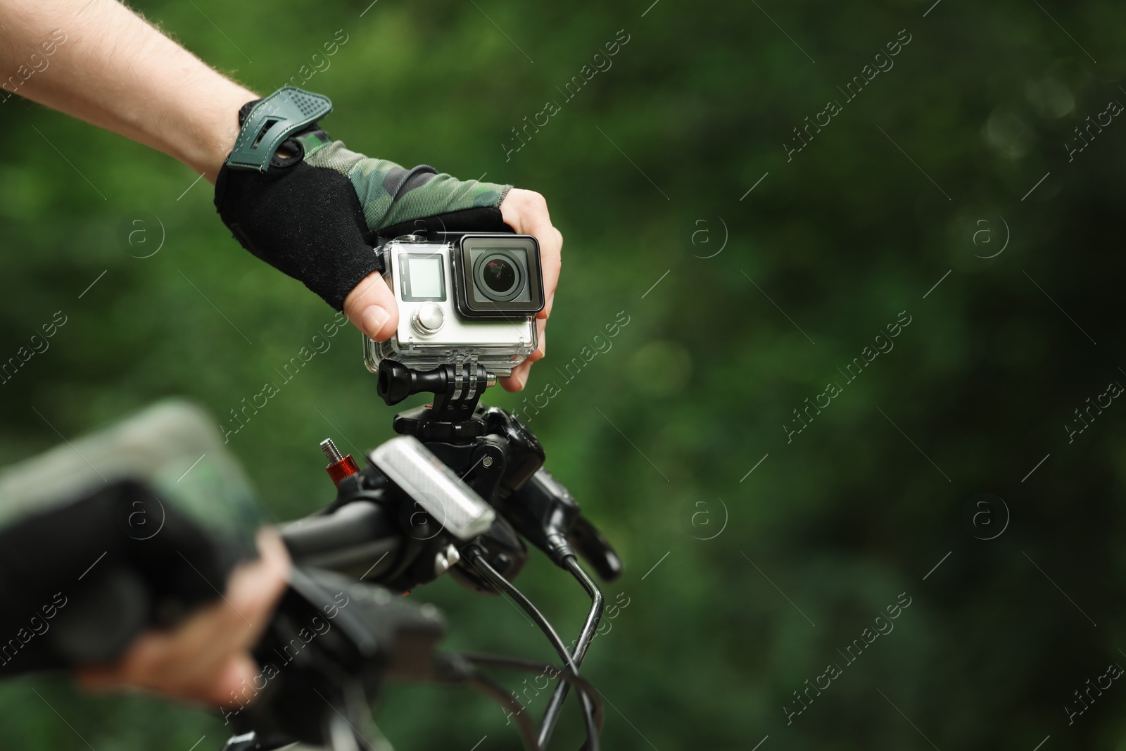 Photo of Man with modern action camera on bicycle outdoors, closeup. Space for text