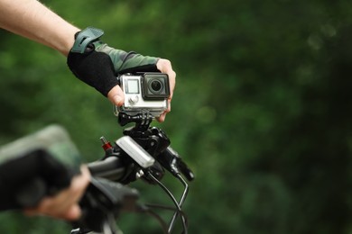 Man with modern action camera on bicycle outdoors, closeup. Space for text