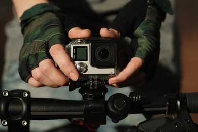 Man with modern action camera on bicycle outdoors, closeup