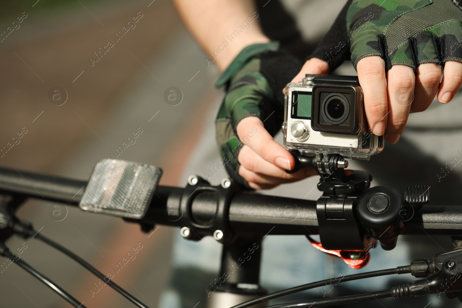 Photo of Man with modern action camera on bicycle outdoors, closeup