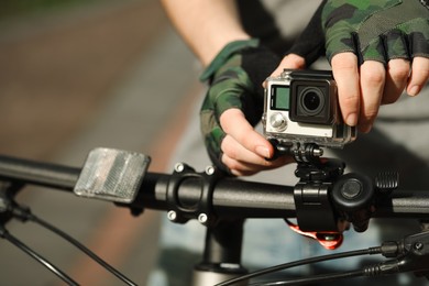 Man with modern action camera on bicycle outdoors, closeup