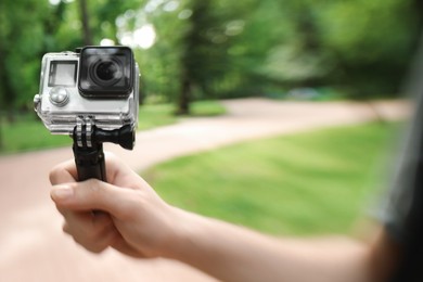 Photo of Man using modern action camera outdoors, closeup