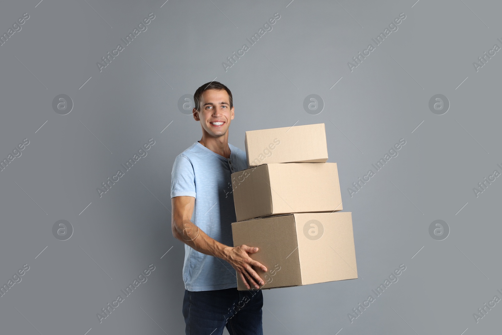 Photo of Moving into new house. Man with cardboard boxes on grey background