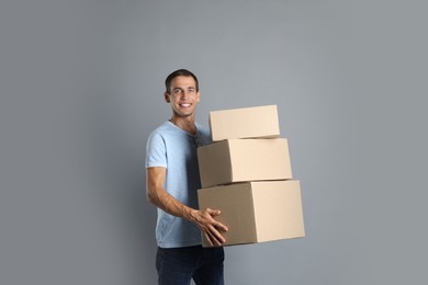 Moving into new house. Man with cardboard boxes on grey background