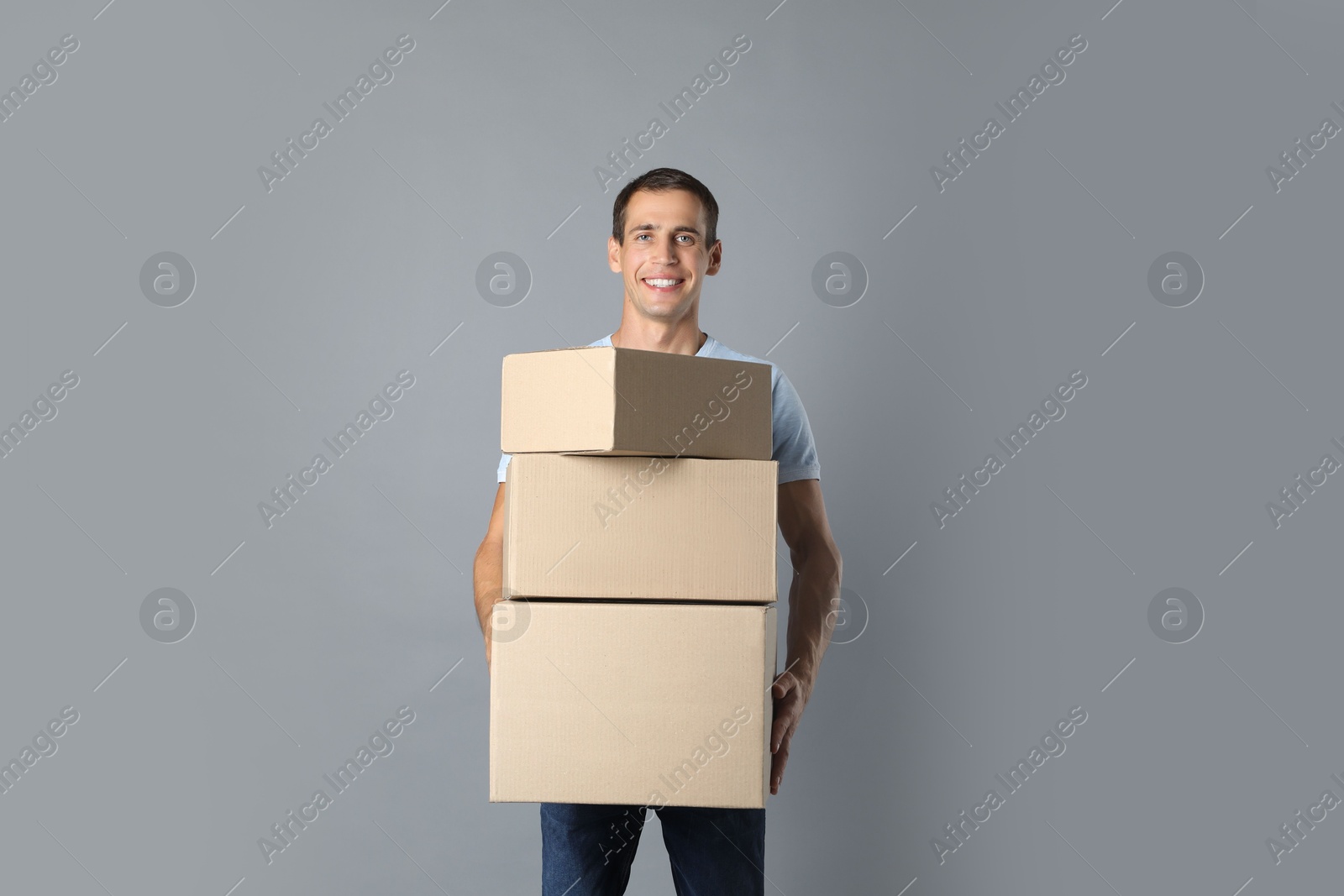 Photo of Moving into new house. Man with cardboard boxes on grey background