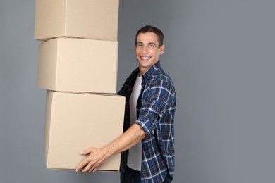 Photo of Moving into new house. Man with cardboard boxes on grey background, space for text