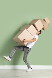 Photo of Moving into new house. Man with cardboard boxes near light green wall