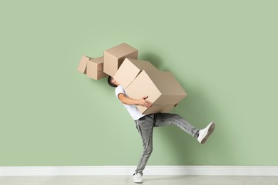 Moving into new house. Man with cardboard boxes near light green wall