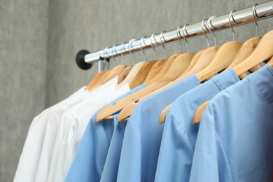 Photo of Different medical workers' uniforms on clothing rack against grey background