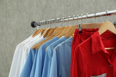 Photo of Different medical workers' uniforms on clothing rack against grey background