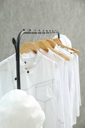 Photo of Chefs' uniforms on clothing rack against grey background, closeup