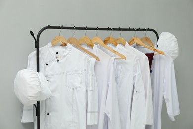 Chefs' uniforms on clothing rack against grey background