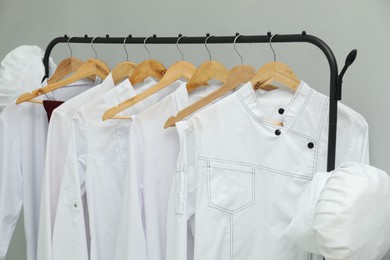 Chefs' uniforms on clothing rack against grey background