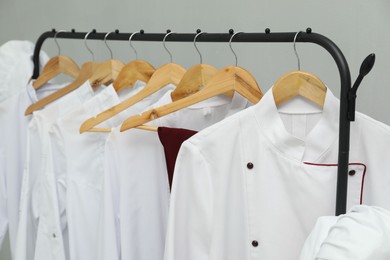 Photo of Chefs' uniforms on clothing rack against grey background, closeup