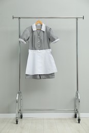 Photo of Maid's uniform on clothing rack near grey wall indoors