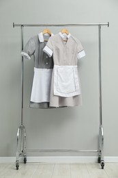 Photo of Maids' uniforms on clothing rack near grey wall indoors