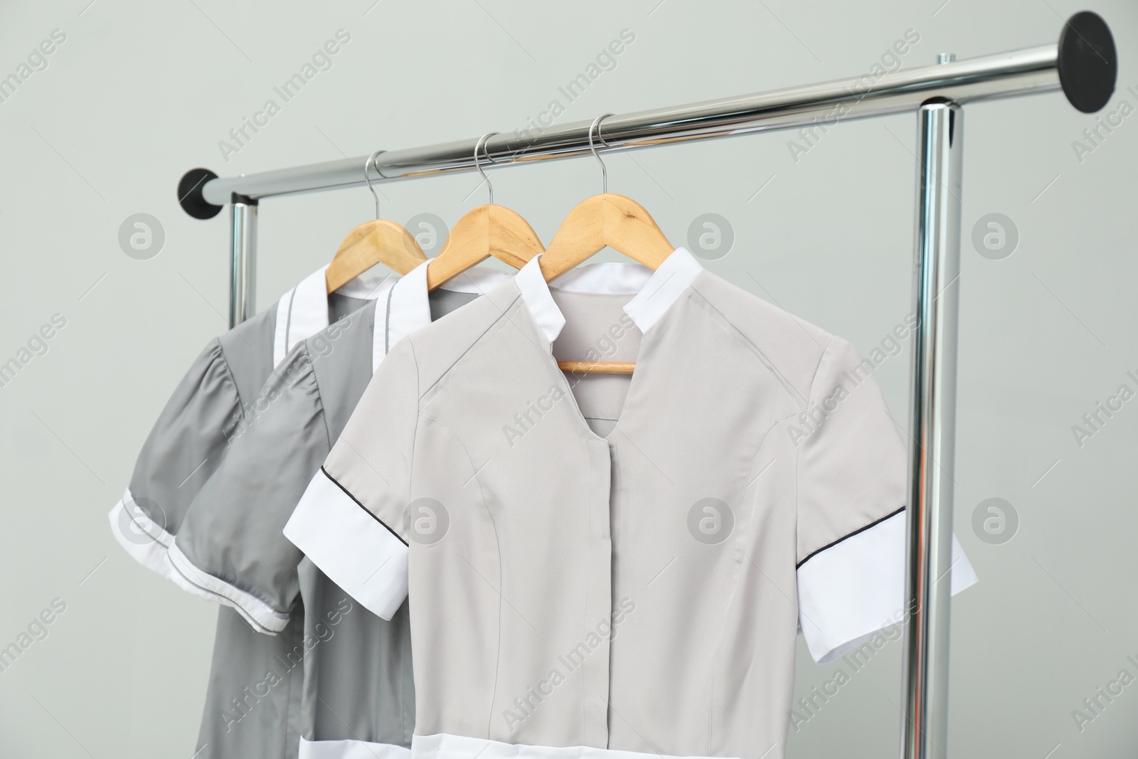 Photo of Maids' uniforms on clothing rack against grey background