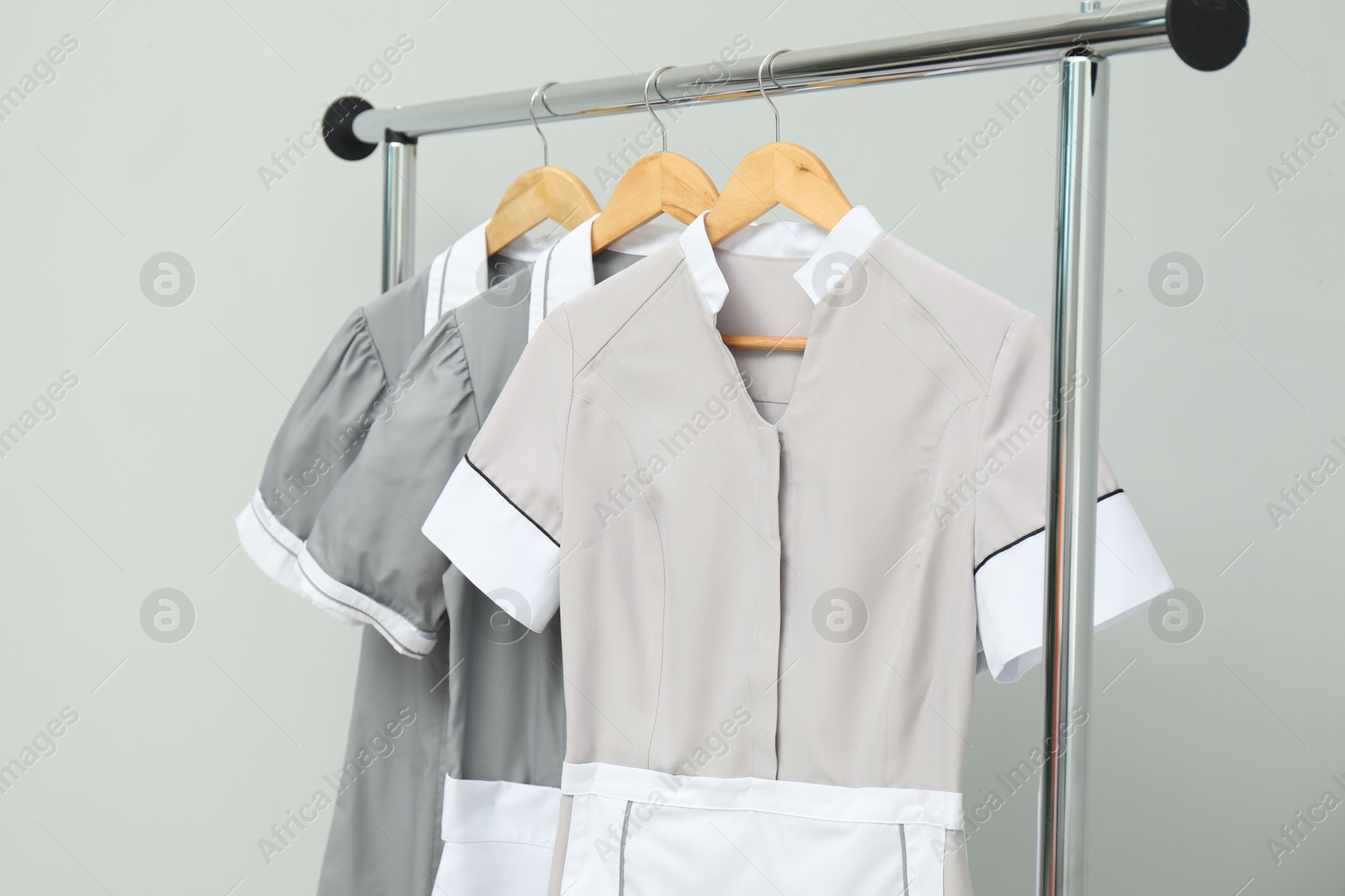 Photo of Maids' uniforms on clothing rack against grey background