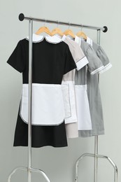 Photo of Maids' uniforms on clothing rack against grey background