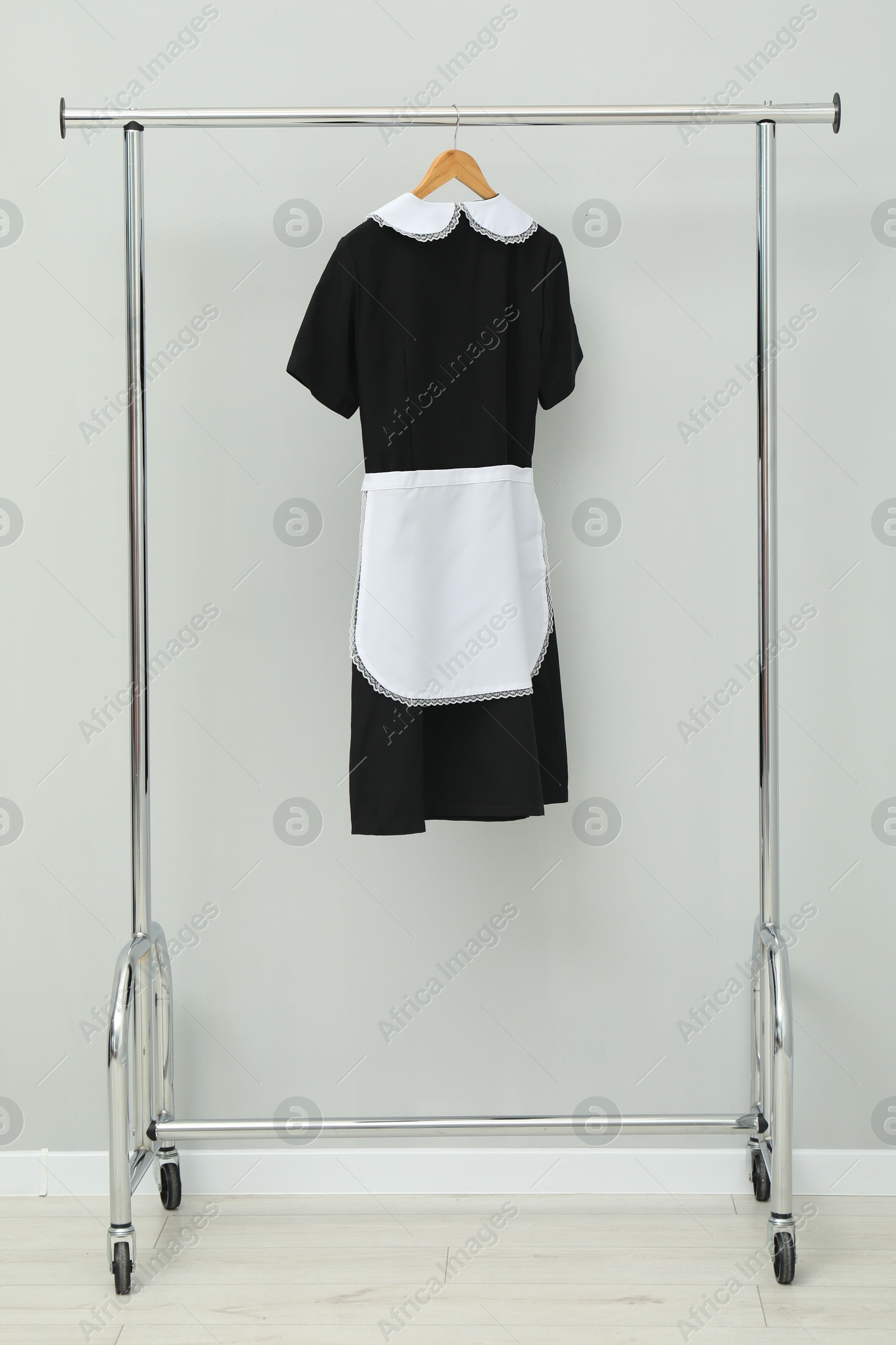 Photo of Maid's uniform on clothing rack near grey wall indoors