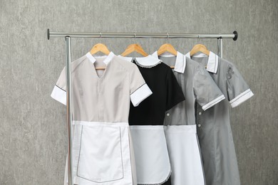 Photo of Maids' uniforms on clothing rack near grey wall