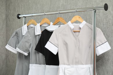 Photo of Maids' uniforms on clothing rack near grey wall