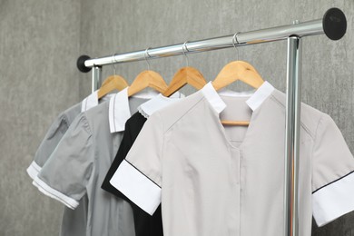 Photo of Maids' uniforms on clothing rack near grey wall