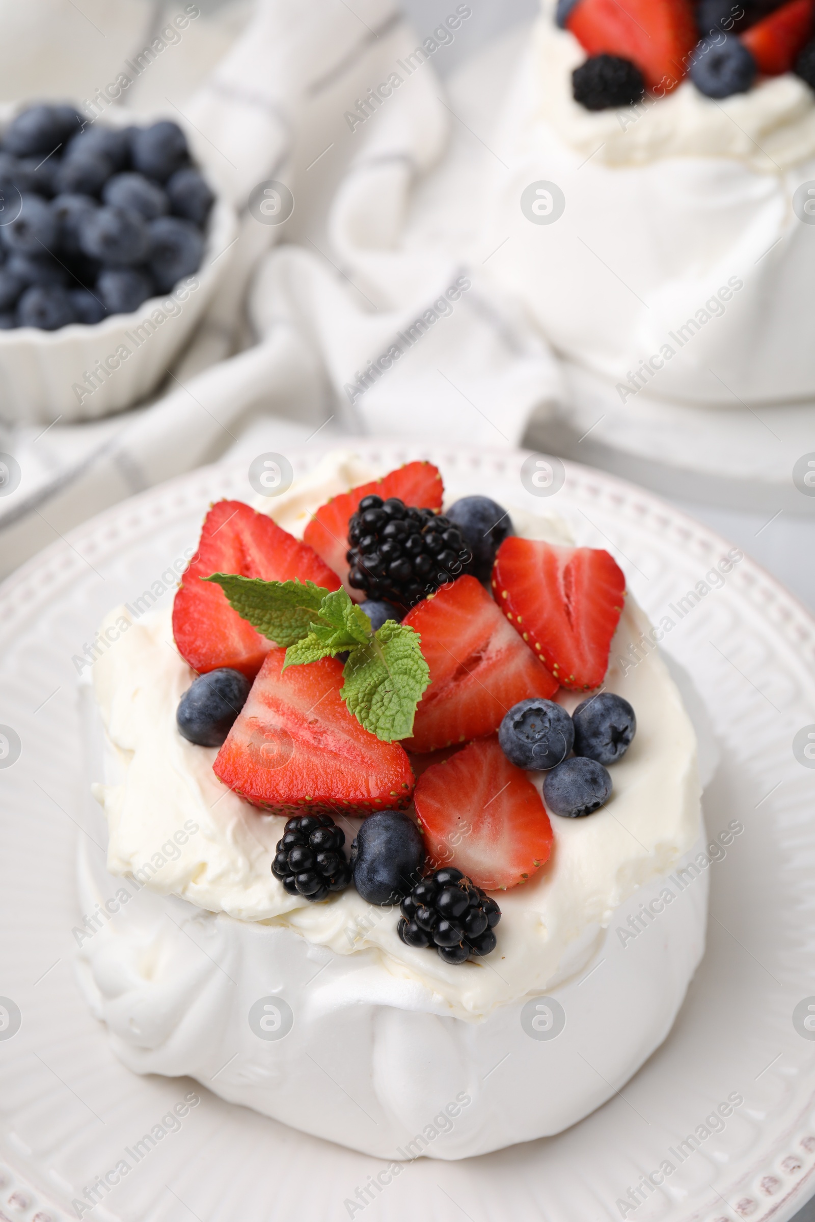 Photo of Pavlova cake (meringue dessert) with whipped cream, fresh berries and mint on table, closeup