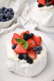 Photo of Pavlova cake (meringue dessert) with whipped cream, fresh berries and mint on table, closeup