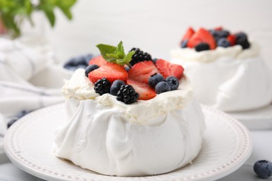 Photo of Pavlova cake (meringue dessert) with whipped cream, fresh berries and mint on table, closeup