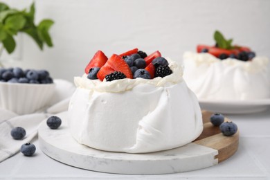 Photo of Pavlova cake (meringue dessert) with whipped cream and fresh berries on white table, closeup