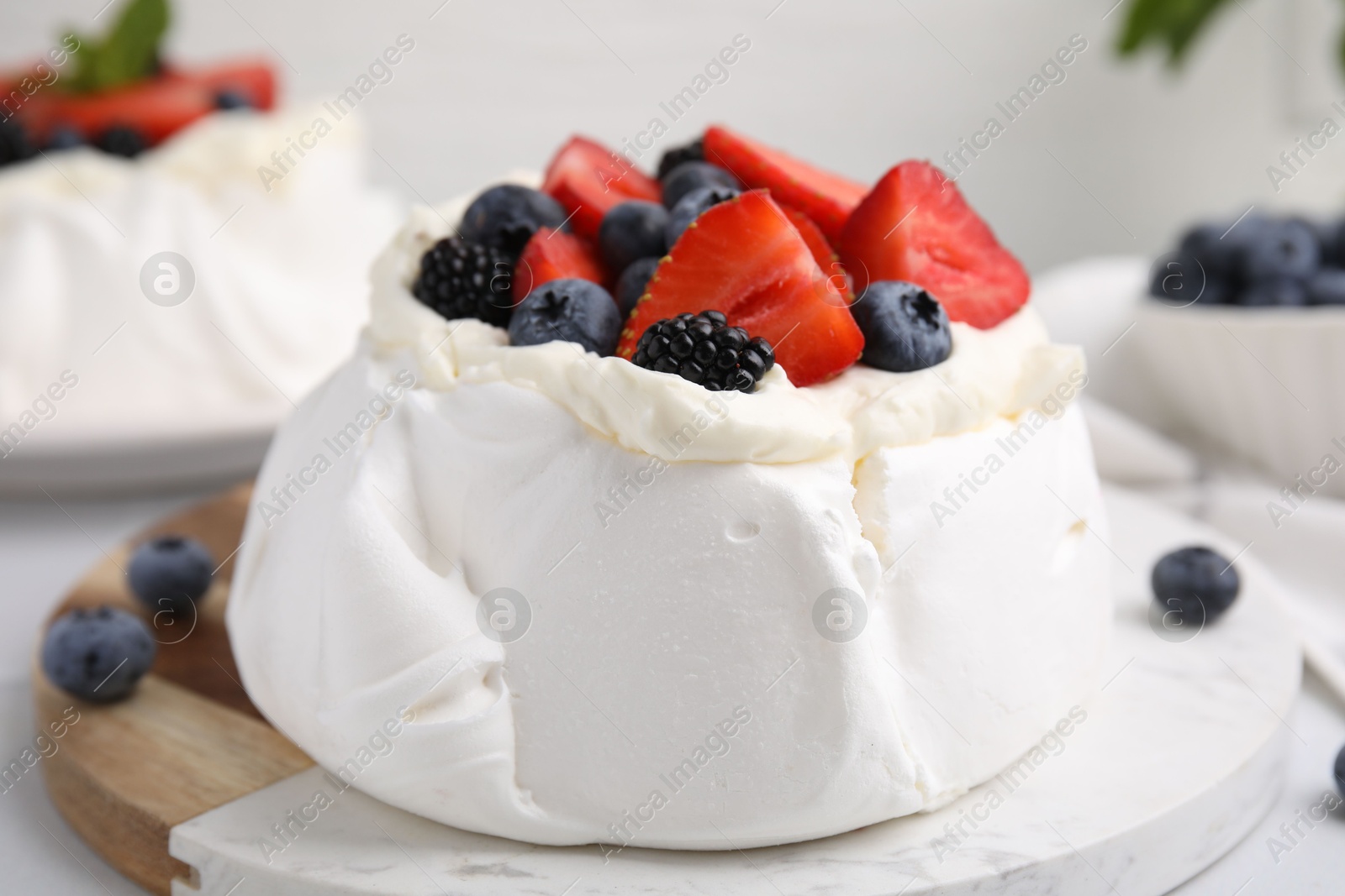 Photo of Pavlova cake (meringue dessert) with whipped cream and fresh berries on table, closeup