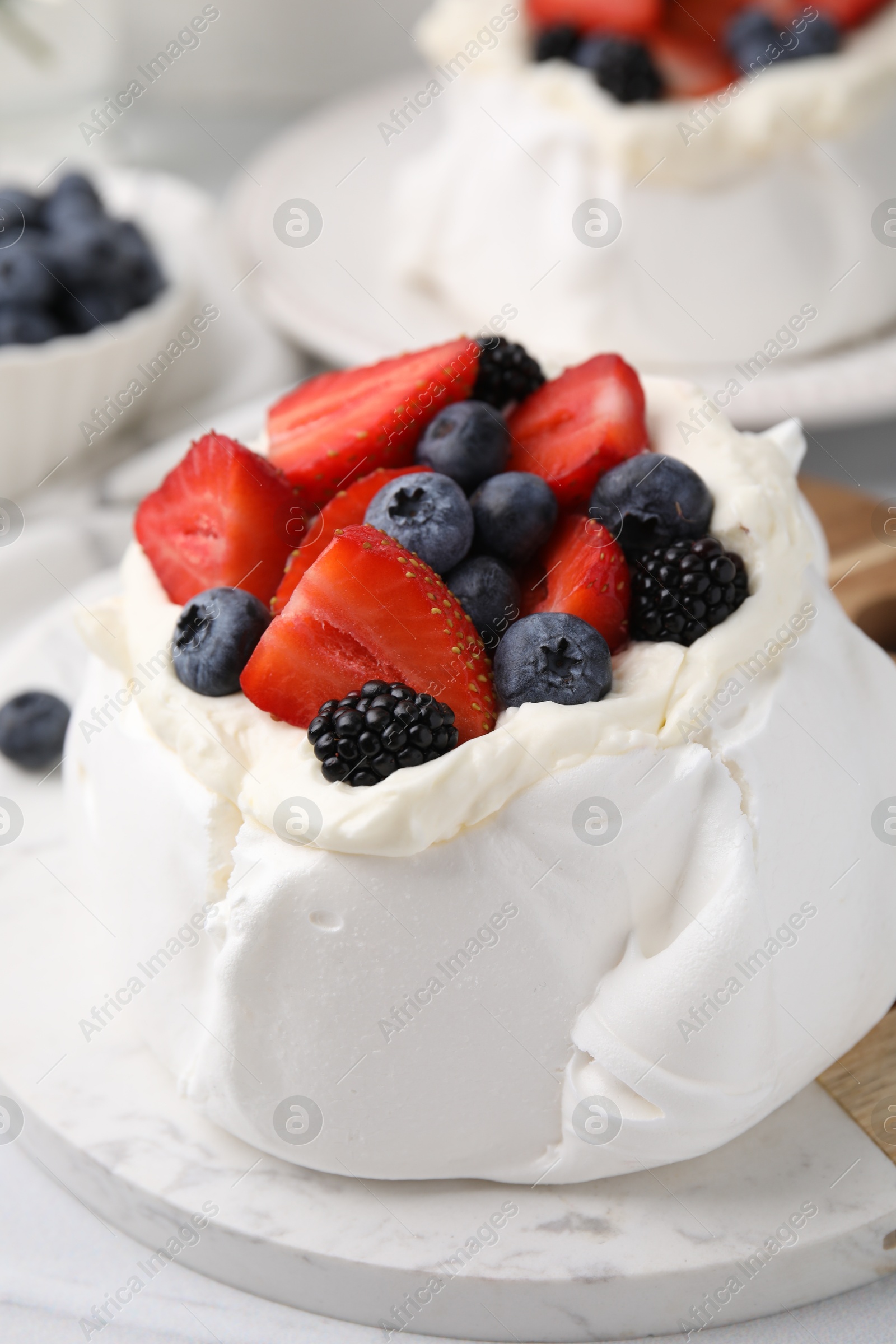 Photo of Pavlova cake (meringue dessert) with whipped cream and fresh berries on table, closeup