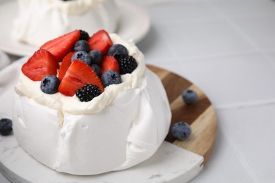 Photo of Pavlova cake (meringue dessert) with whipped cream and fresh berries on white table, closeup