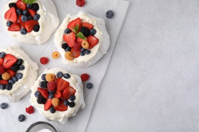 Photo of Pavlova cake (meringue dessert) with whipped cream and fresh berries on light grey table, flat lay. Space for text