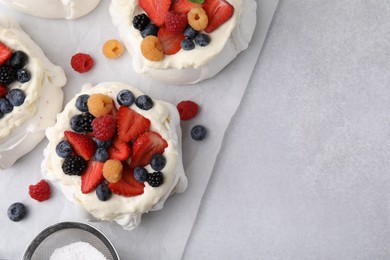 Photo of Pavlova cake (meringue dessert) with whipped cream and fresh berries on light grey table, flat lay. Space for text