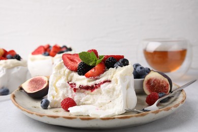 Photo of Pavlova cake (meringue dessert) with whipped cream, fresh berries, mint and fig on table, closeup