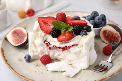 Photo of Pavlova cake (meringue dessert) with whipped cream, fresh berries, mint and fig on table, closeup