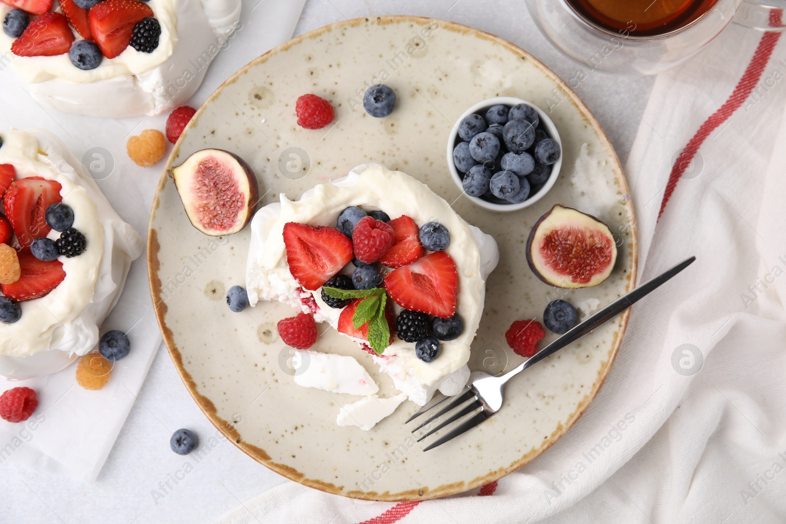 Photo of Pavlova cake (meringue dessert) with whipped cream, fresh berries, mint and fig on light table, top view