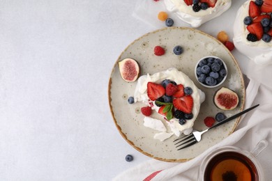 Photo of Pavlova cake (meringue dessert) with whipped cream, fresh berries, mint and fig on light table, top view. Space for text