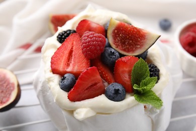 Photo of Pavlova cake (meringue dessert) with whipped cream, fresh berries, mint and fig on table, closeup