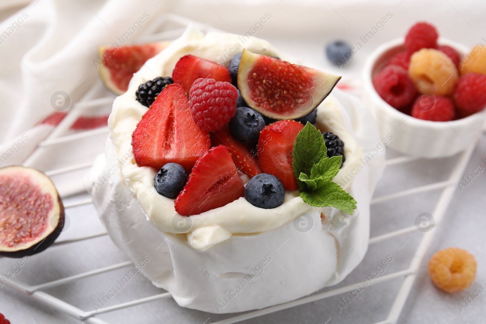 Photo of Pavlova cake (meringue dessert) with whipped cream, fresh berries, mint and fig on table, closeup