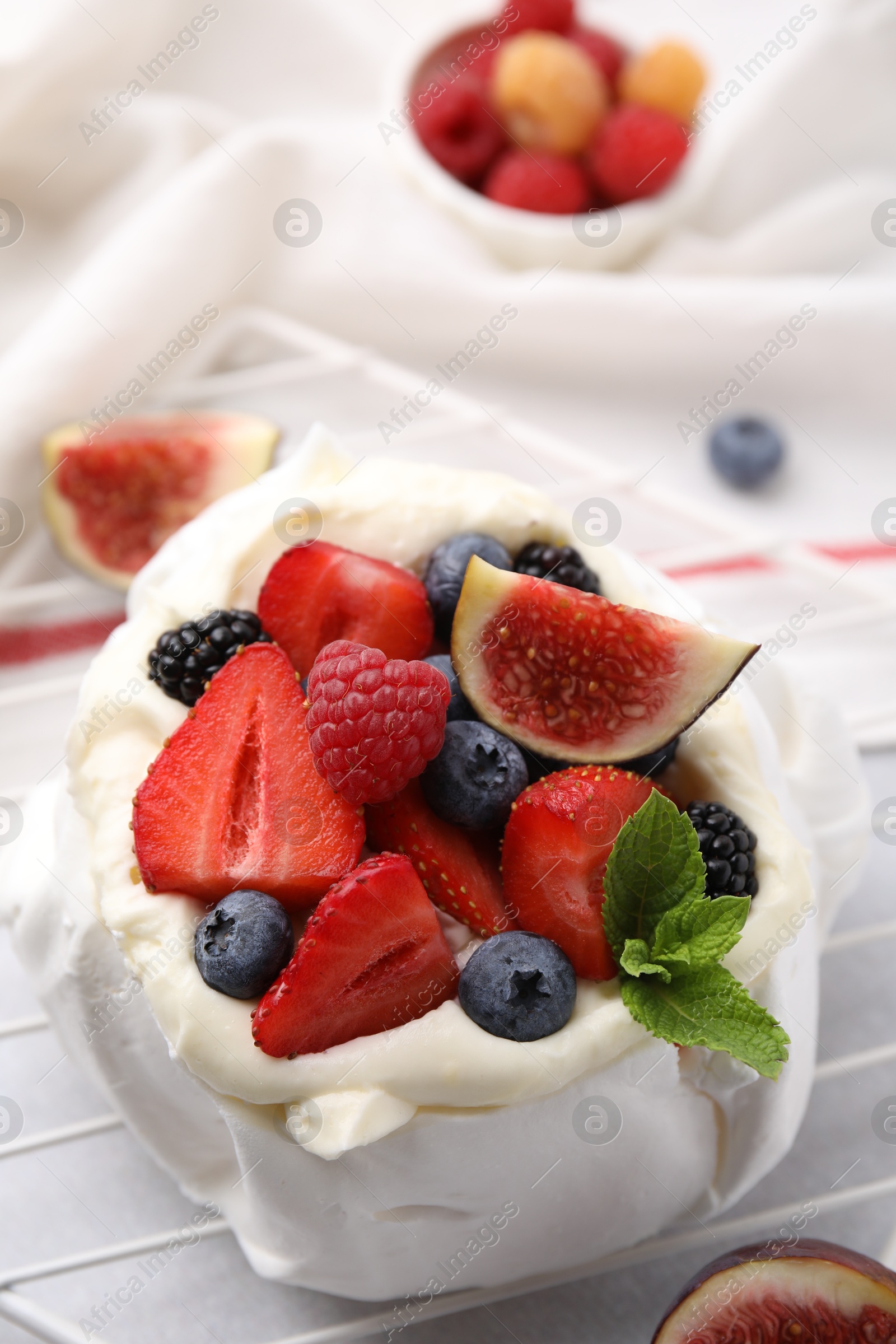 Photo of Pavlova cake (meringue dessert) with whipped cream, fresh berries, mint and fig on table, closeup