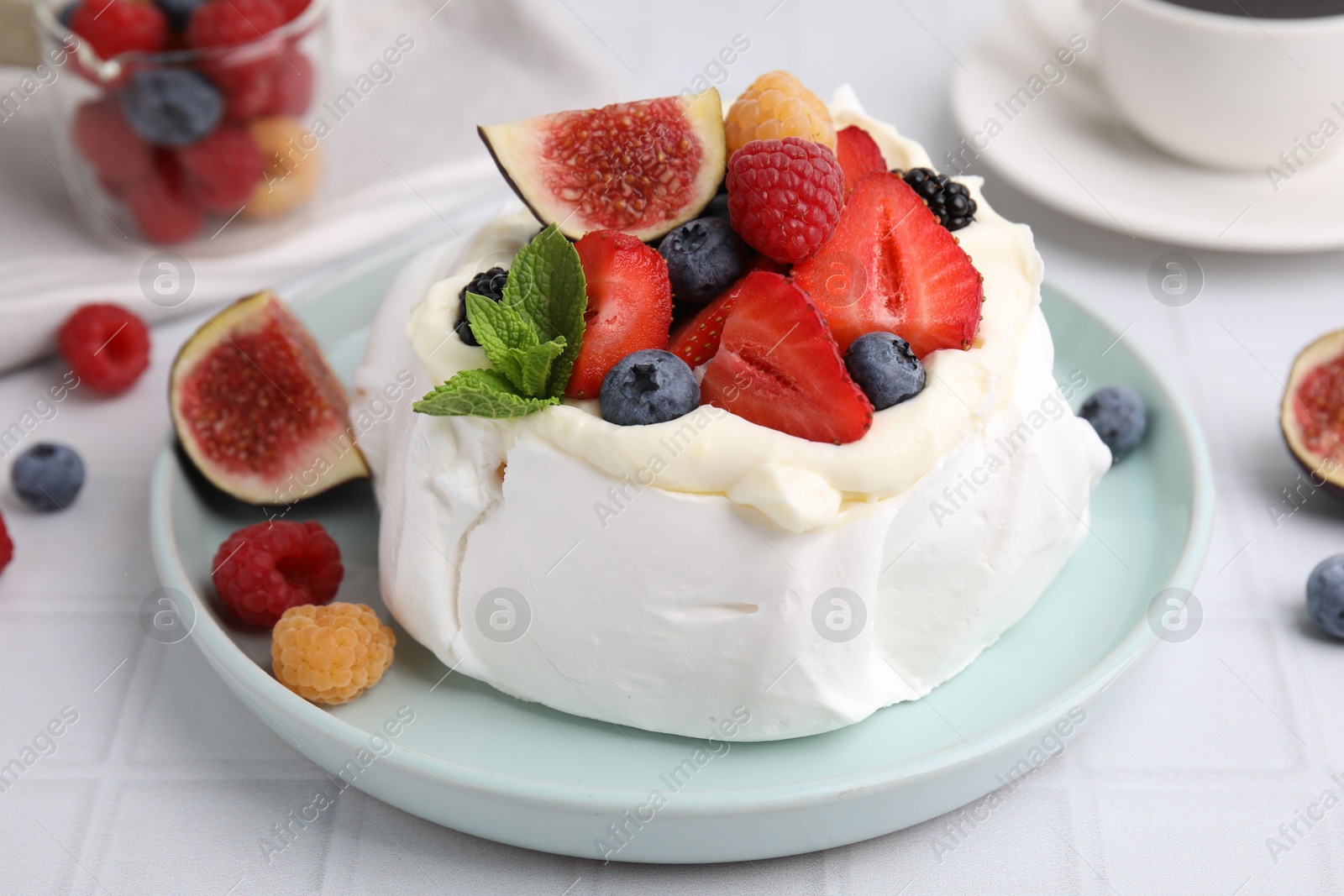 Photo of Pavlova cake (meringue dessert) with whipped cream, fresh berries, mint and fig on white table, closeup