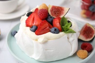 Photo of Pavlova cake (meringue dessert) with whipped cream, fresh berries, mint and fig on table, closeup